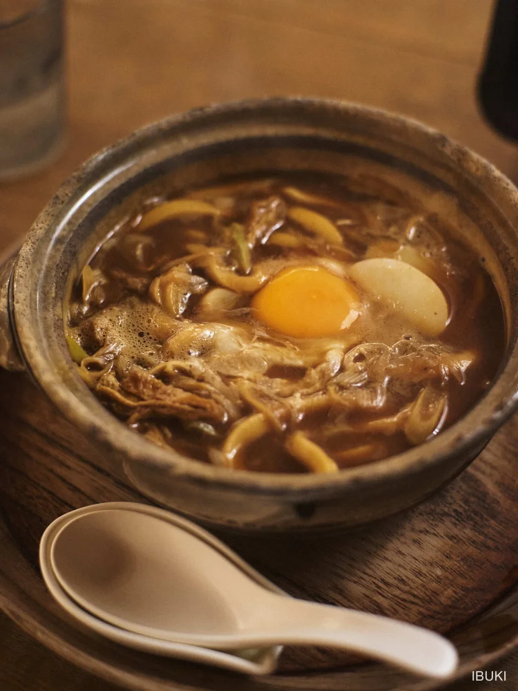 フード 土鍋のカレーうどんに生卵を落としたカット